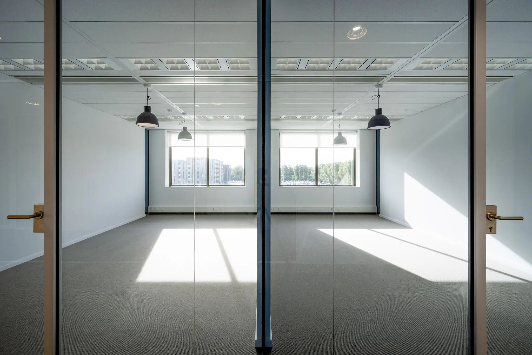 Leeg, modern kantoorruimte met grote ramen en hanglampen aan het Airportplein in Rotterdam.